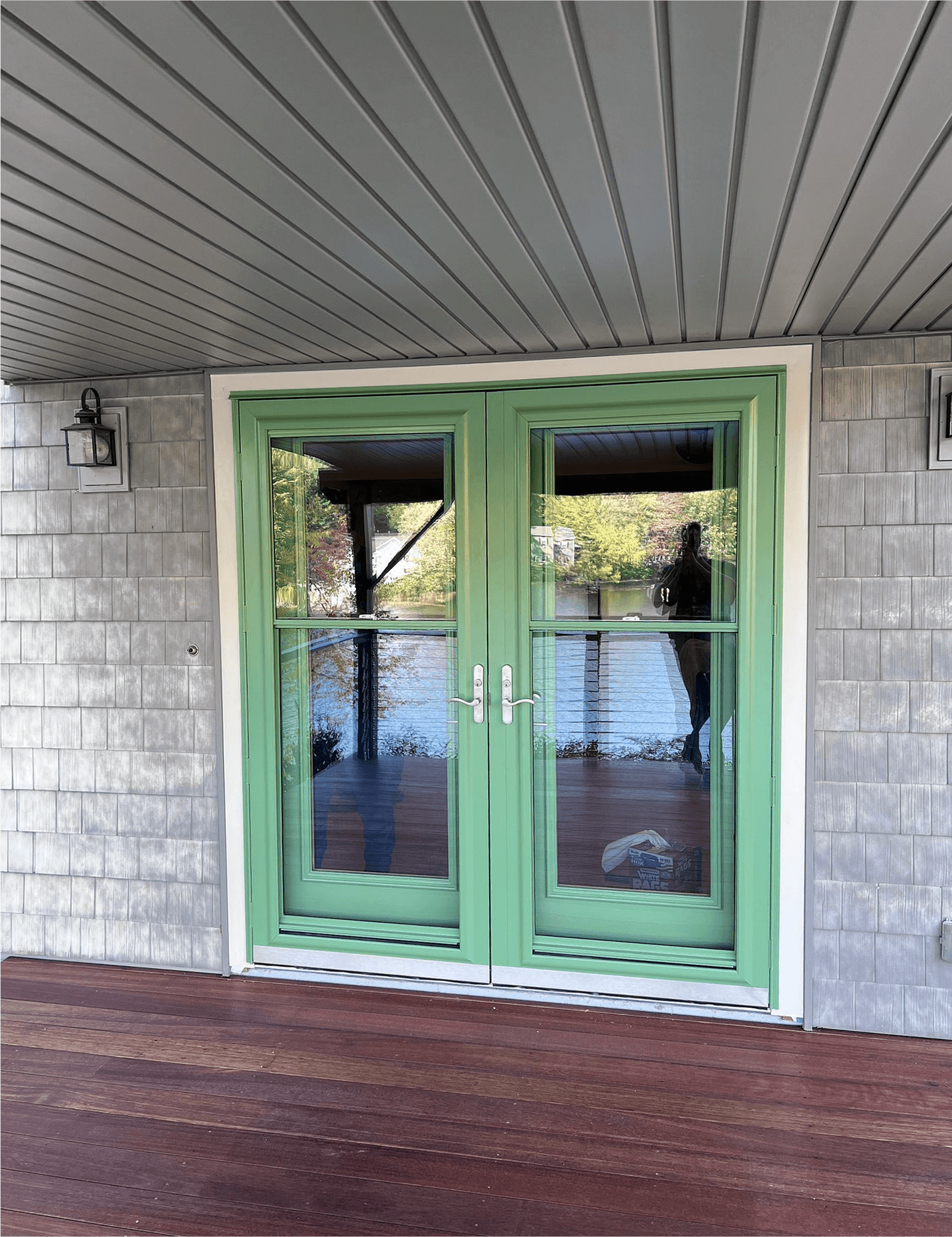 Double glass entry doors with green trim on a gray house.