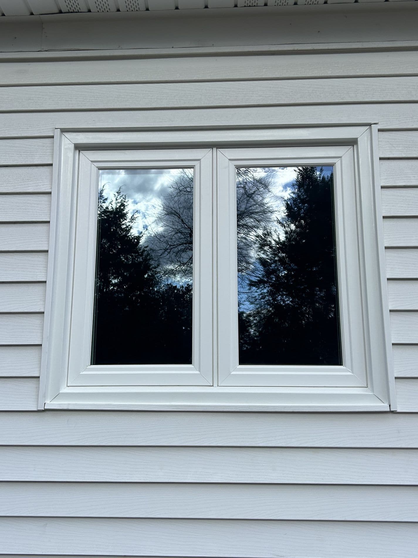 Twin casement windows on a white house.