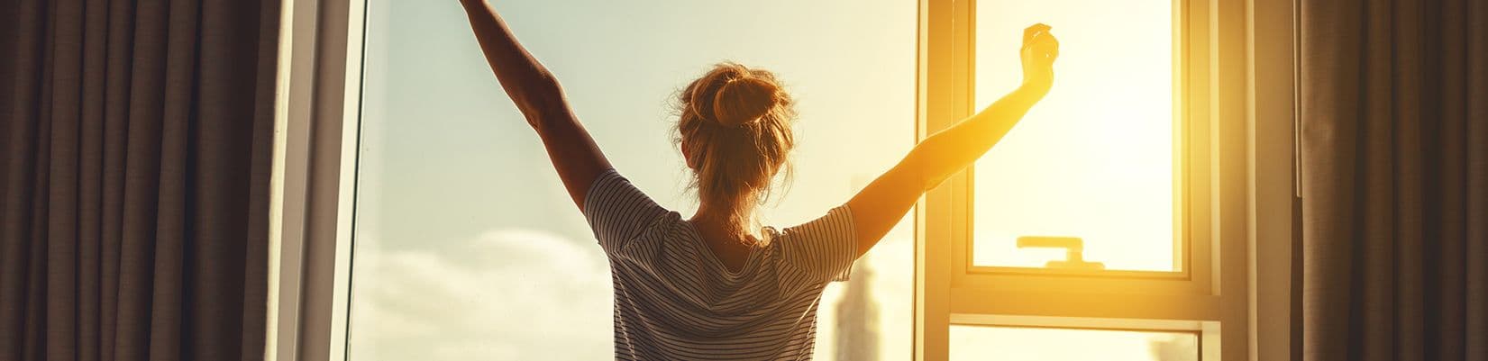 A person facing away from camera with arms raised overhead.