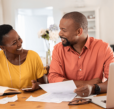 People smile at each other as they look over paperwork at a table.
