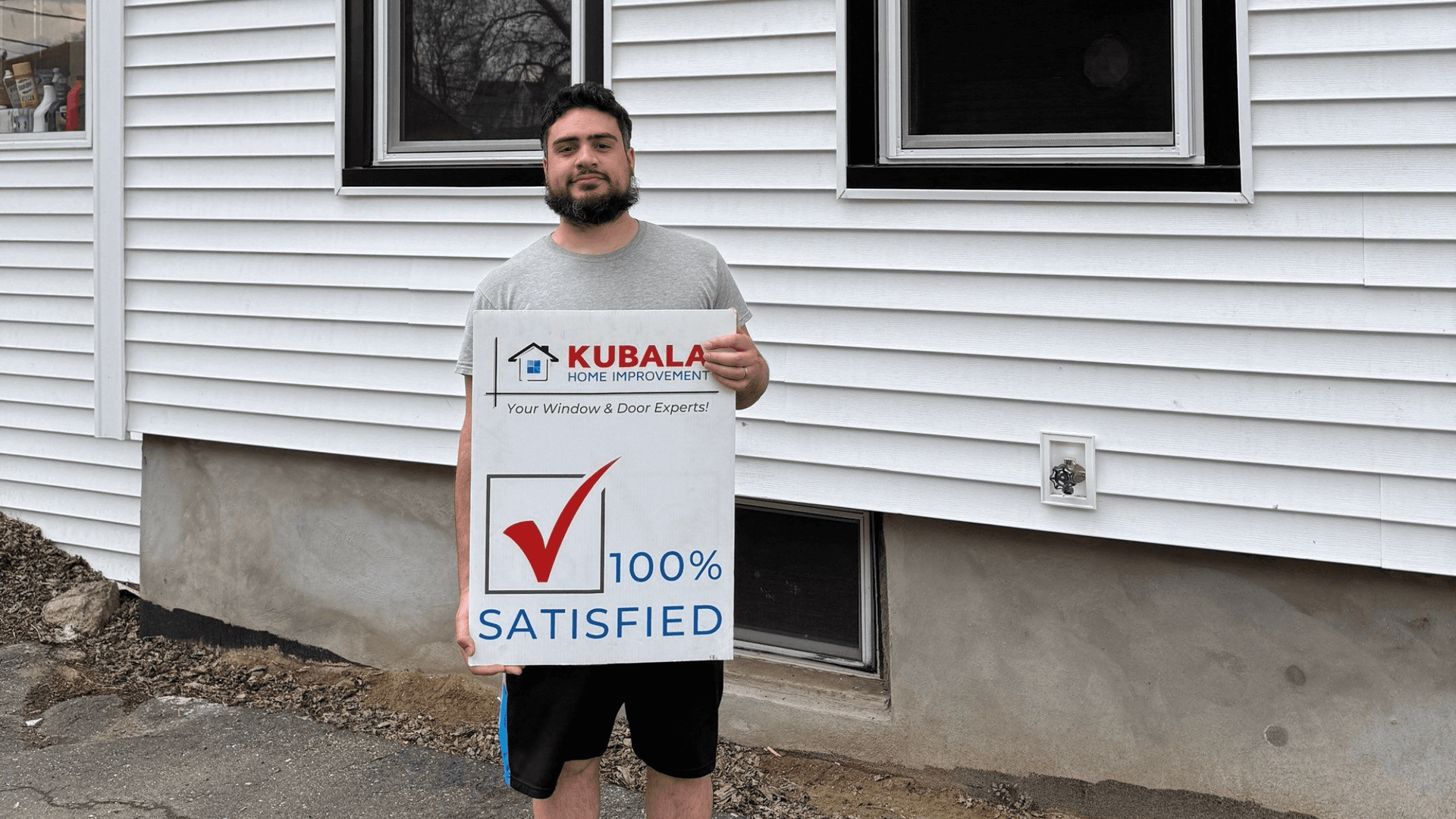 Picture of Octavio smiling and holding a "100% Satisfied" sign in front of his new windows in Springfield, MA.